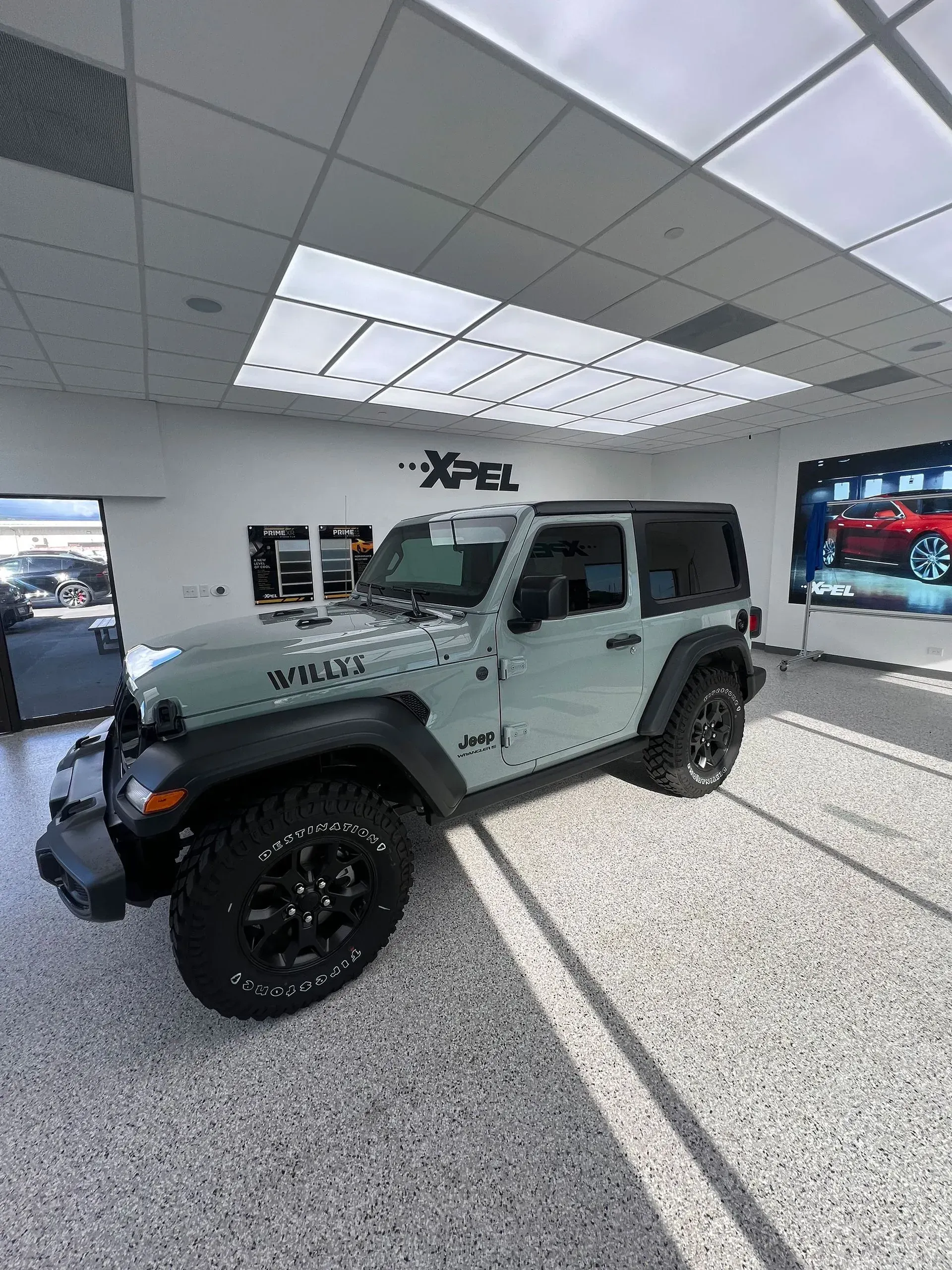 Light green Jeep Wrangler in a showroom.