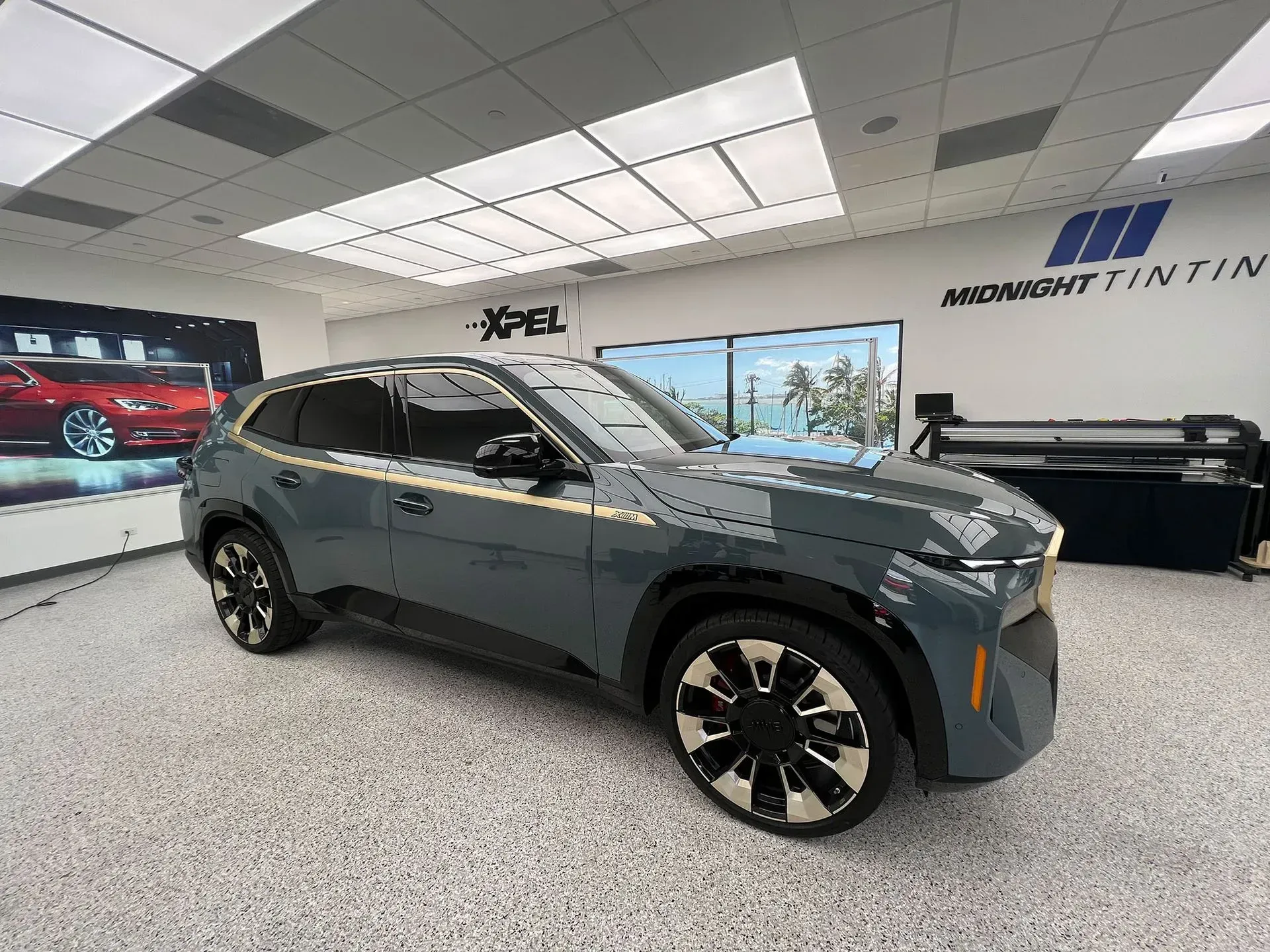 Blue SUV parked in a showroom with tinted windows. Gold trim, black wheels. 