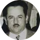 Black-and-white portrait of a man with dark hair and a mustache, wearing a suit and tie