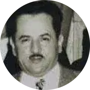Black-and-white portrait of a man with dark hair and a mustache, wearing a suit and tie