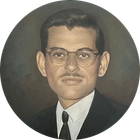 Formal portrait of a man in glasses, suit, and tie against a dark circular background