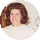 Portrait of a smiling person with dark curly hair wearing a white top