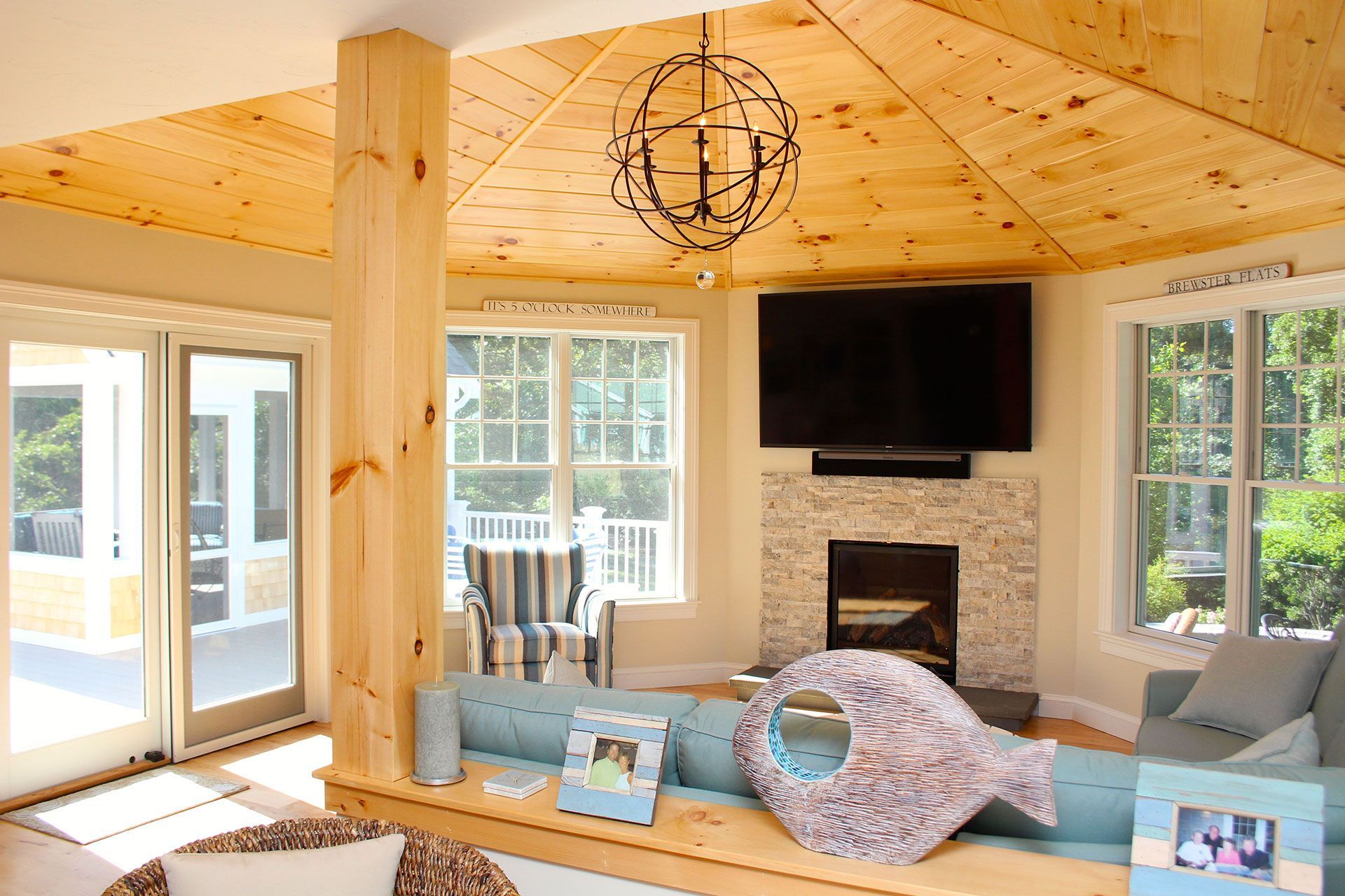 Living room with wooden ceiling, fireplace, and a fish-shaped pillow on a blue sofa.