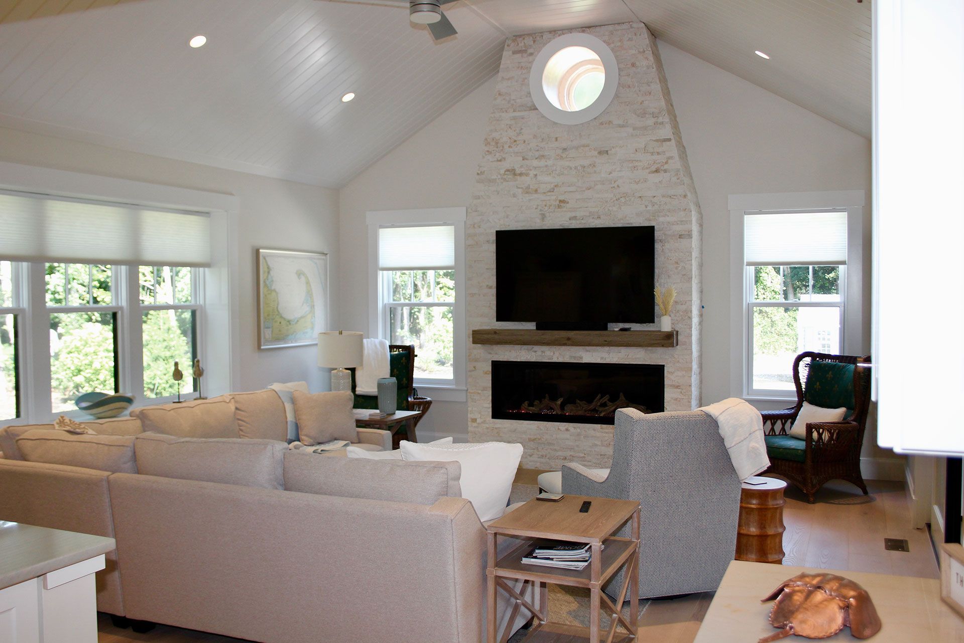Bright living room with white brick fireplace, TV, beige sectional sofa, windows, and wooden floors.