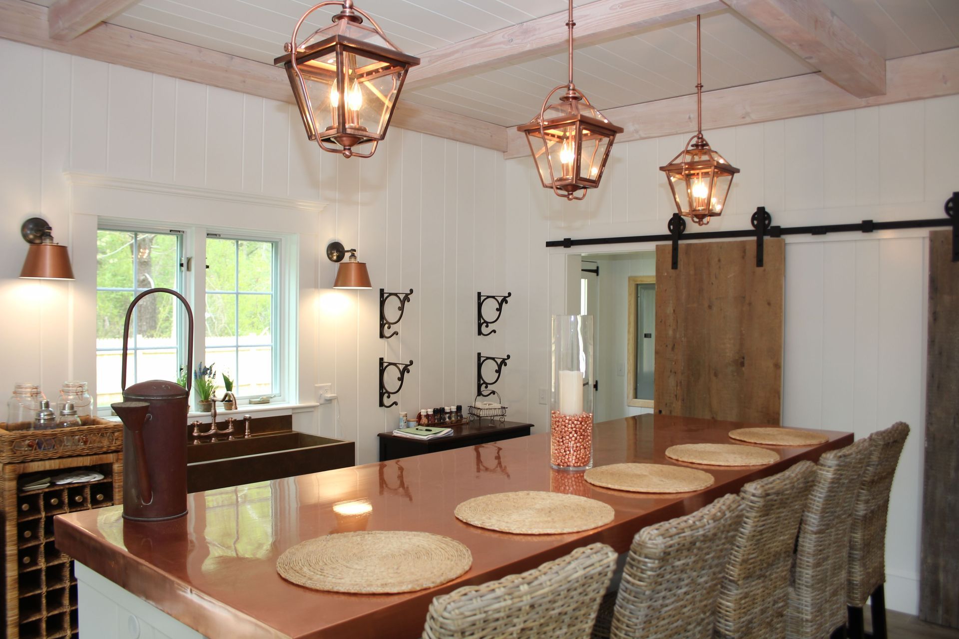 Kitchen with copper countertop, pendant lights, barn door, and woven barstools
