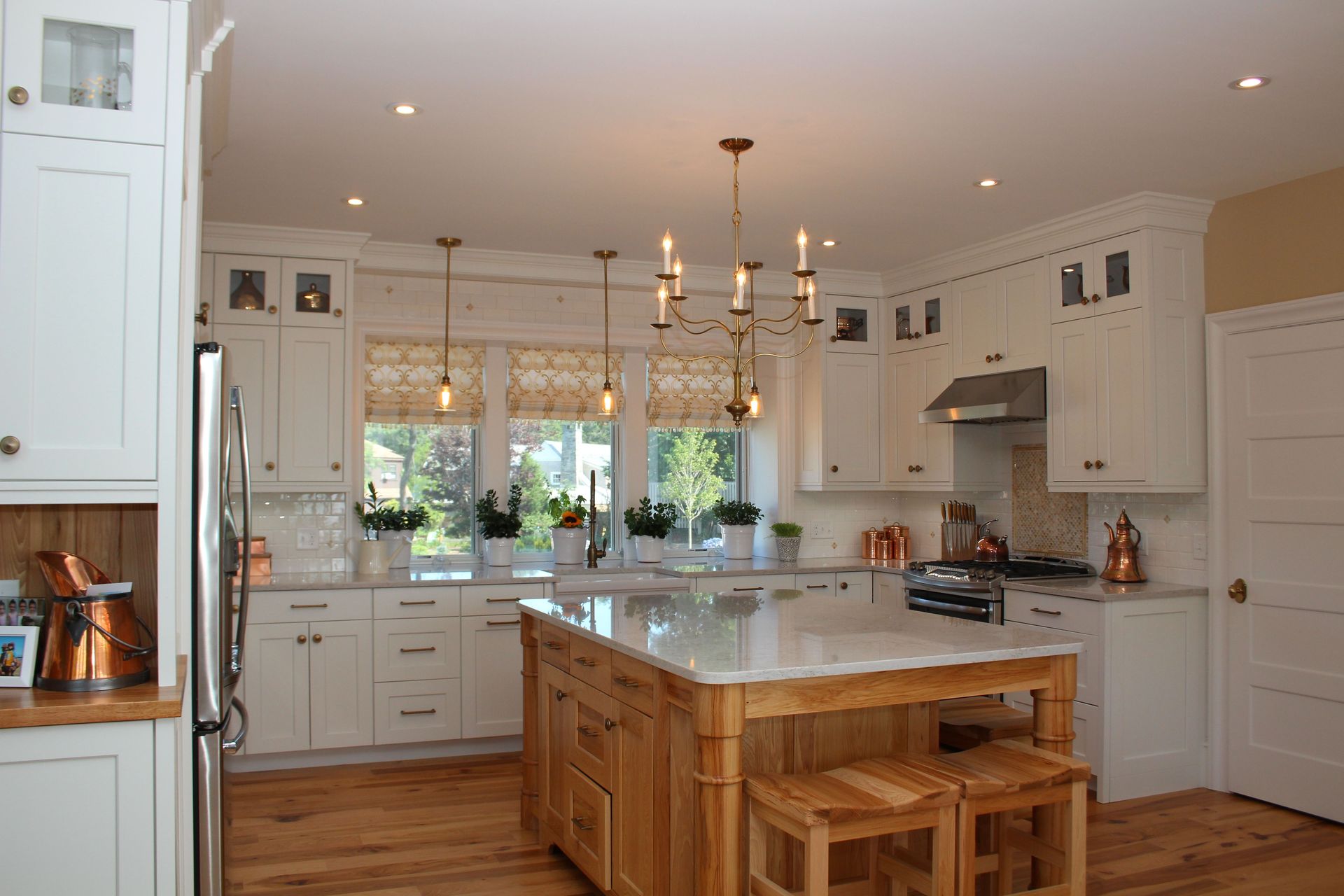 Bright kitchen with white cabinets, a wooden island, and gold light fixtures