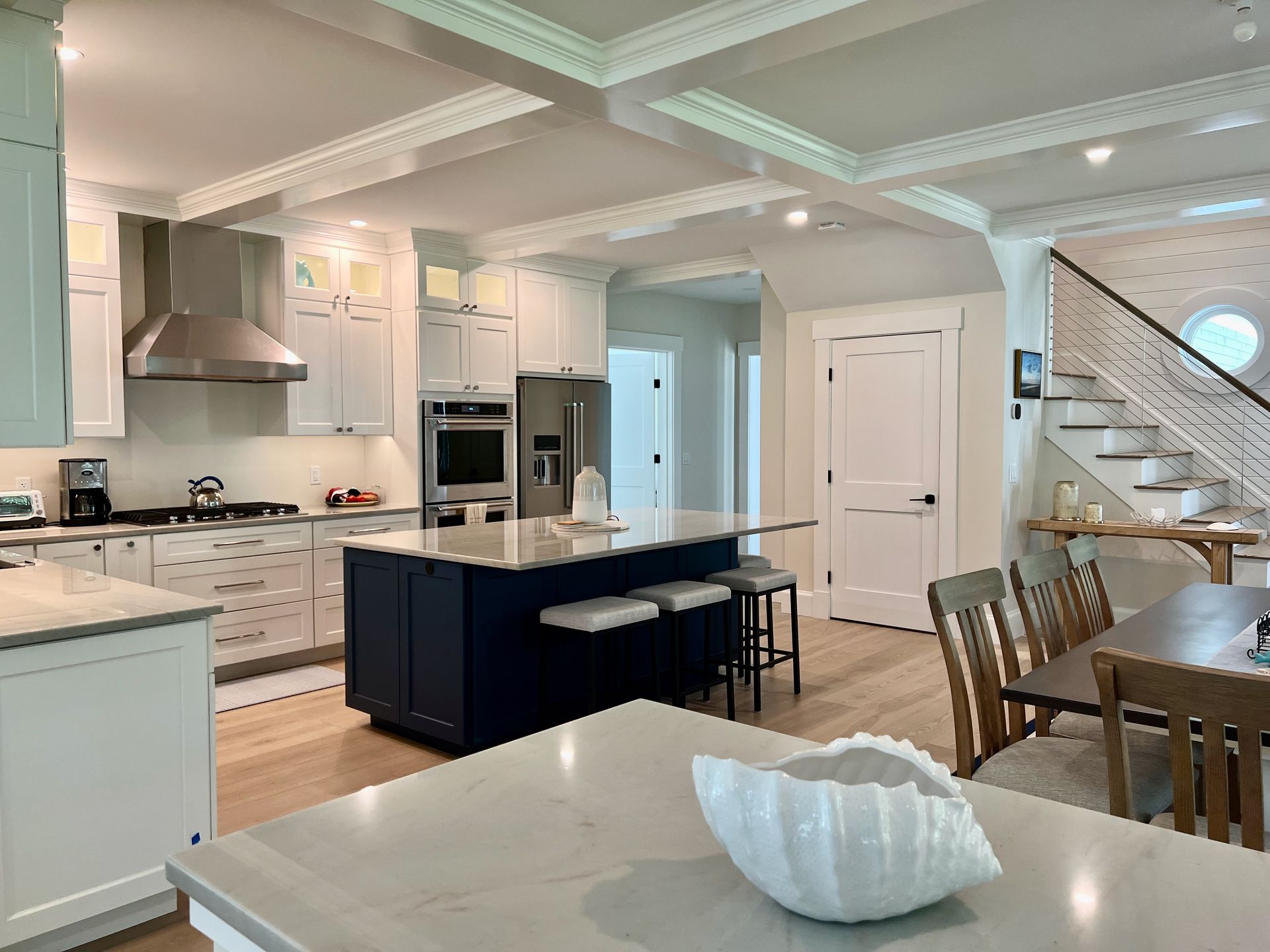 Spacious kitchen with white cabinets, navy island, stainless steel appliances, and wood floors