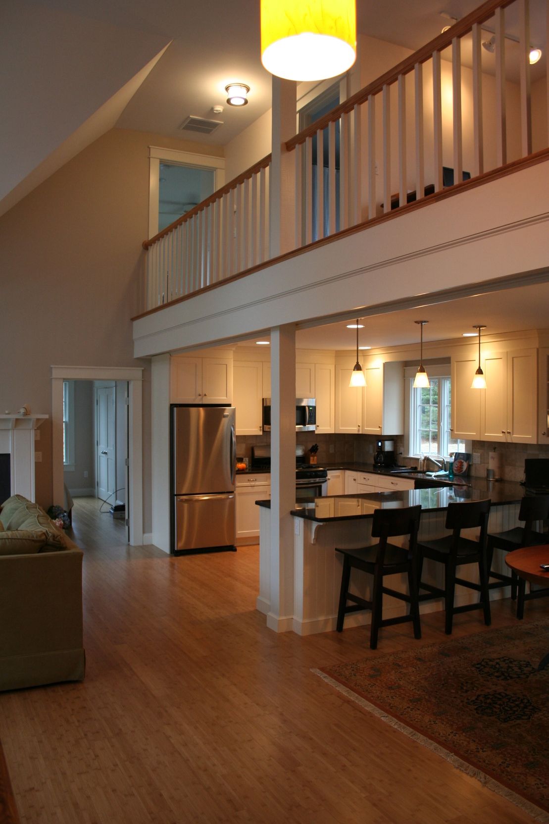 Spacious open-concept home with a kitchen, dining area, and loft. Light wood floors and white walls, stainless steel appliances