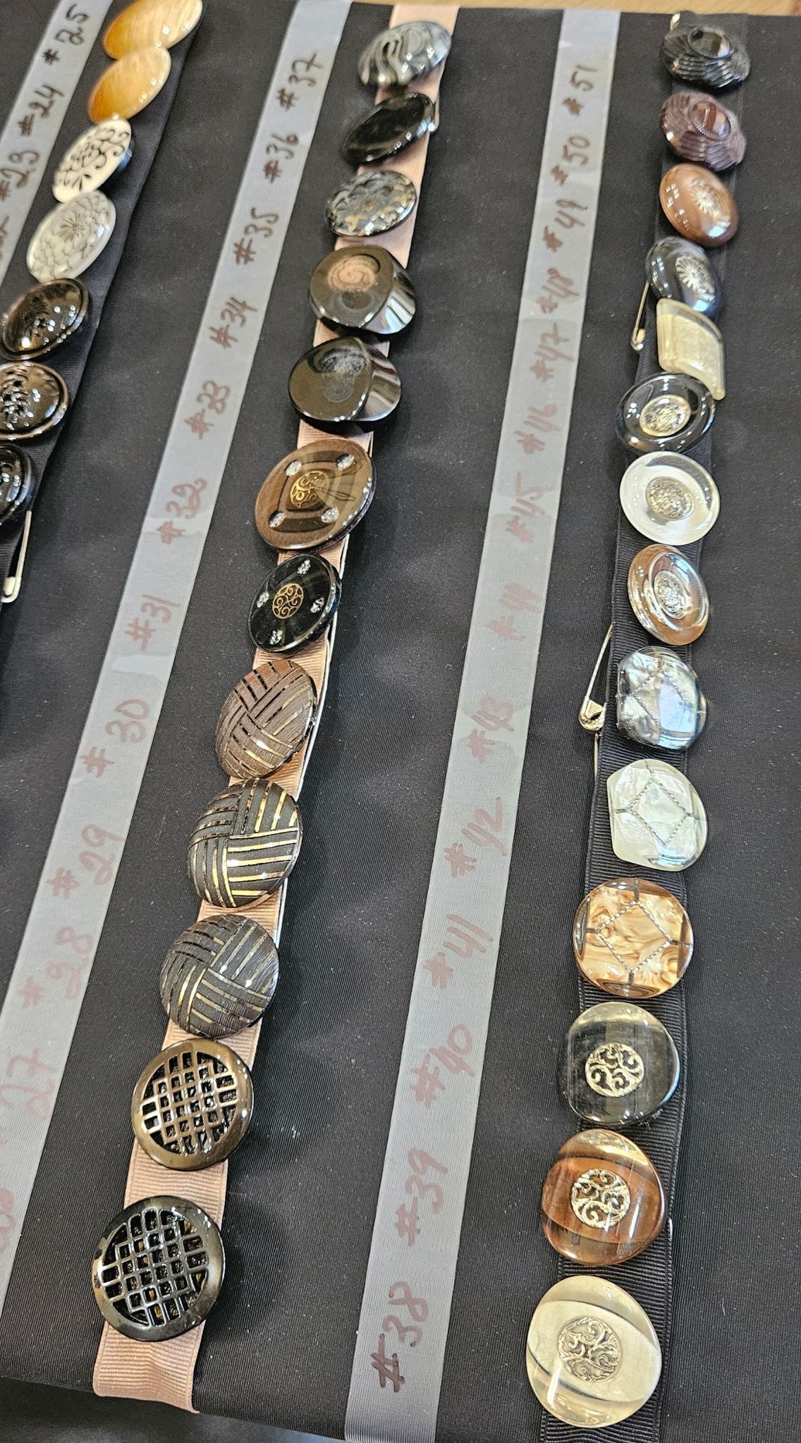 Rows of assorted wristwatches arranged vertically on a gray display surface.
