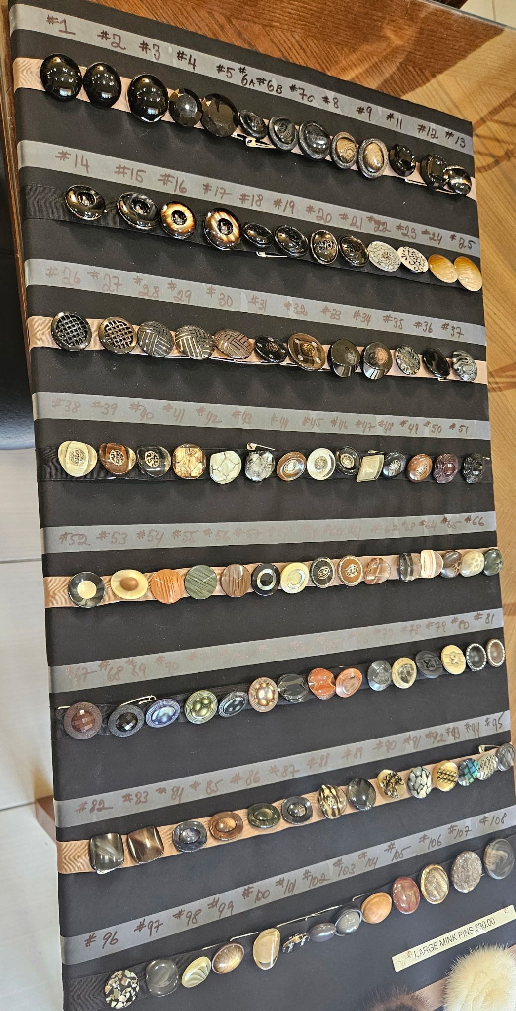 Display of multiple rows of assorted wristwatches mounted on a black wall
