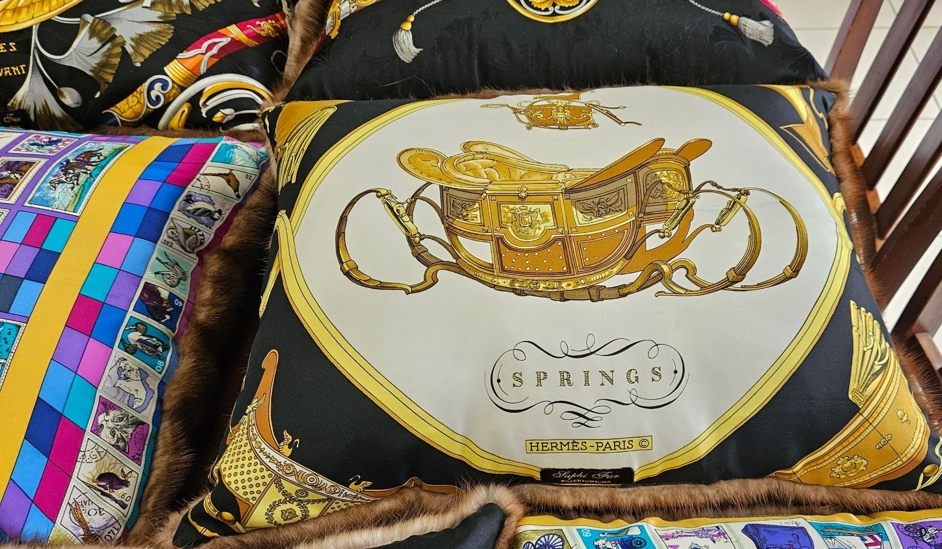 Decorative cushion with a gold teapot and cups design on a colorful patterned sofa