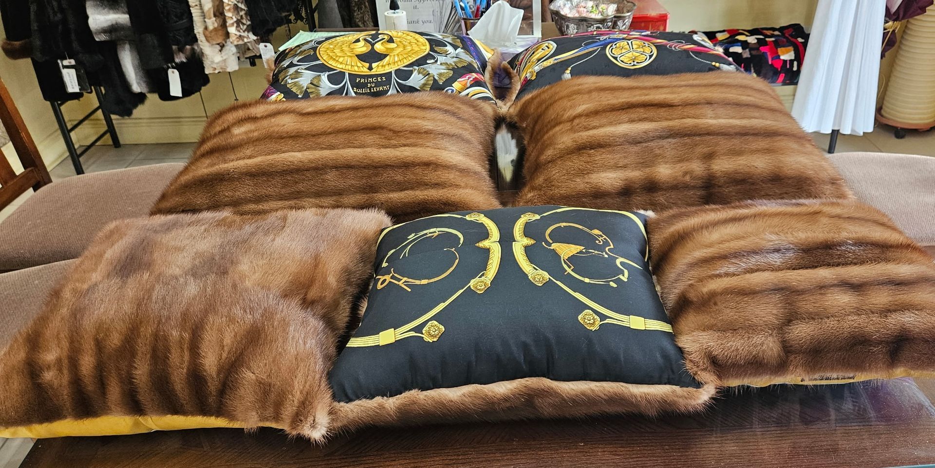 Assorted fur-like pillows and cushions arranged on a bed, including brown and black-and-gold designs.