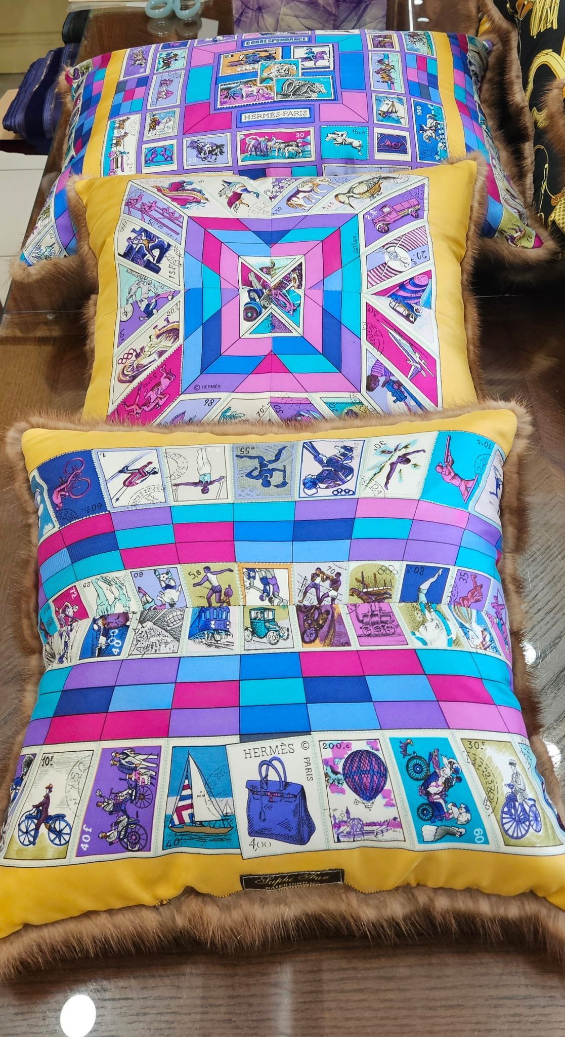 Two colorful patchwork quilts draped over a chair, with blue, pink, purple, and tan patterns.