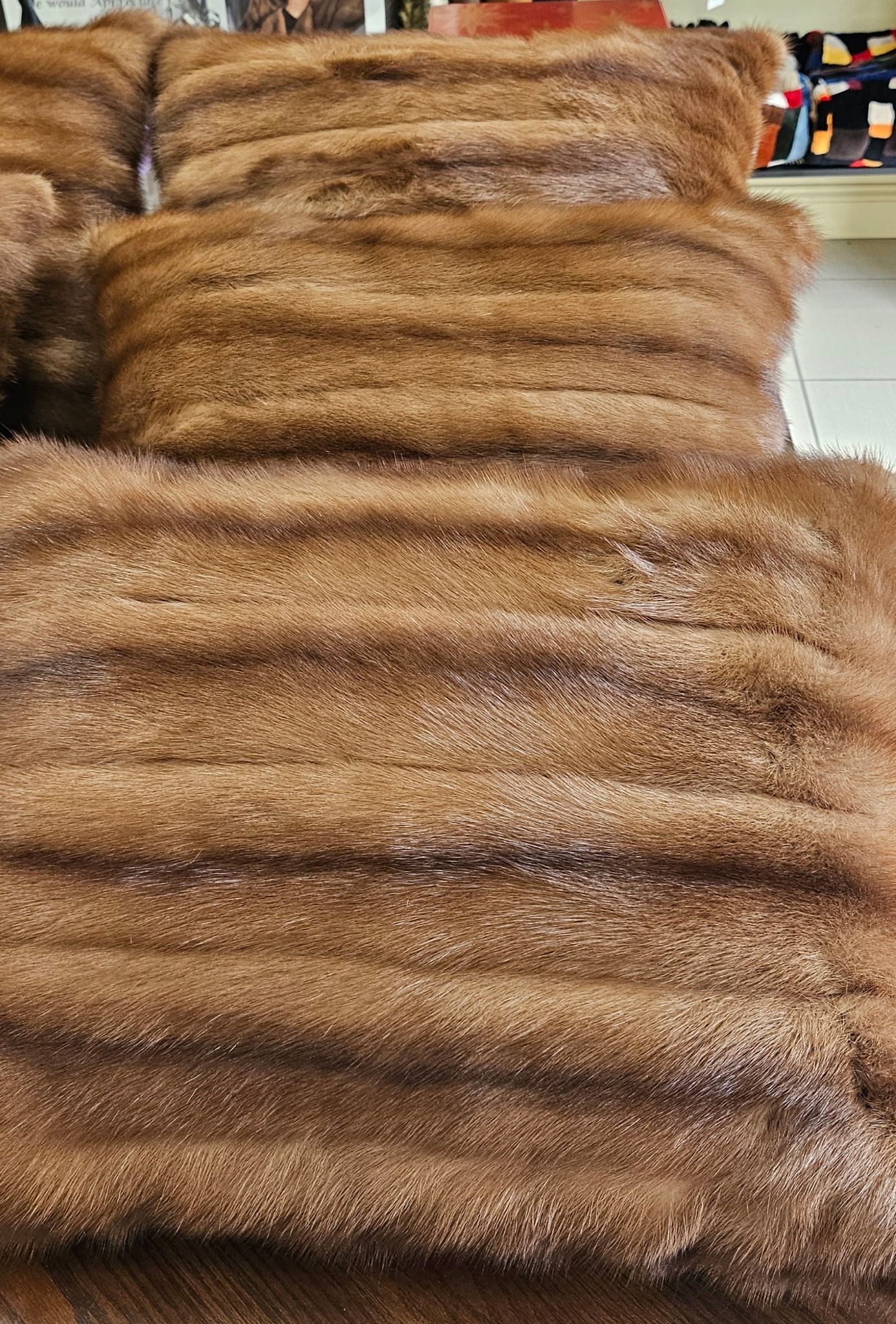 Stacked brown fur pelts or blankets arranged in neat layers on a display shelf.