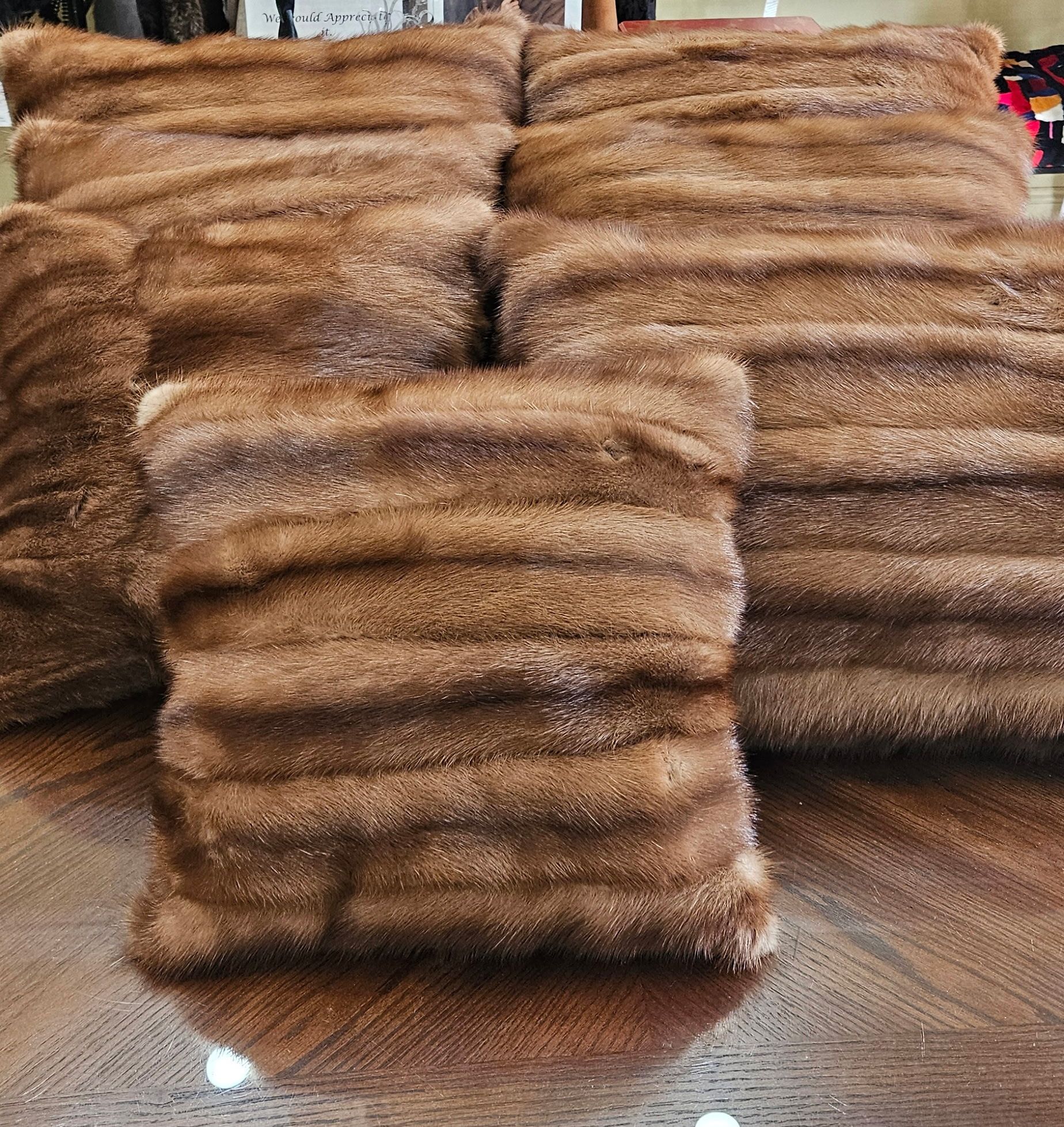 Stacks of folded brown faux fur throws or blankets on a wooden floor indoors