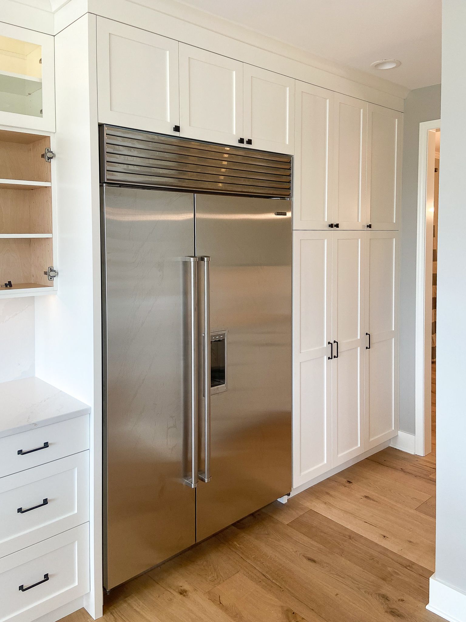 A stainless steel refrigerator in a kitchen with white cabinets.