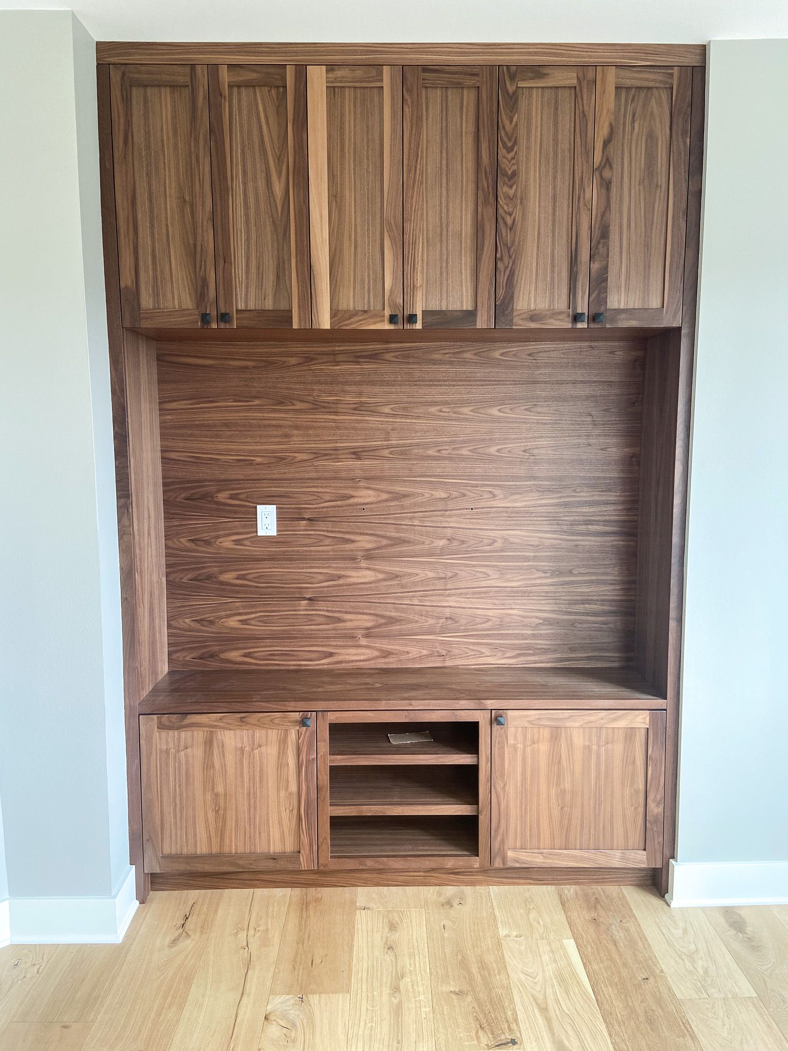 A wooden entertainment center in a living room with hardwood floors.