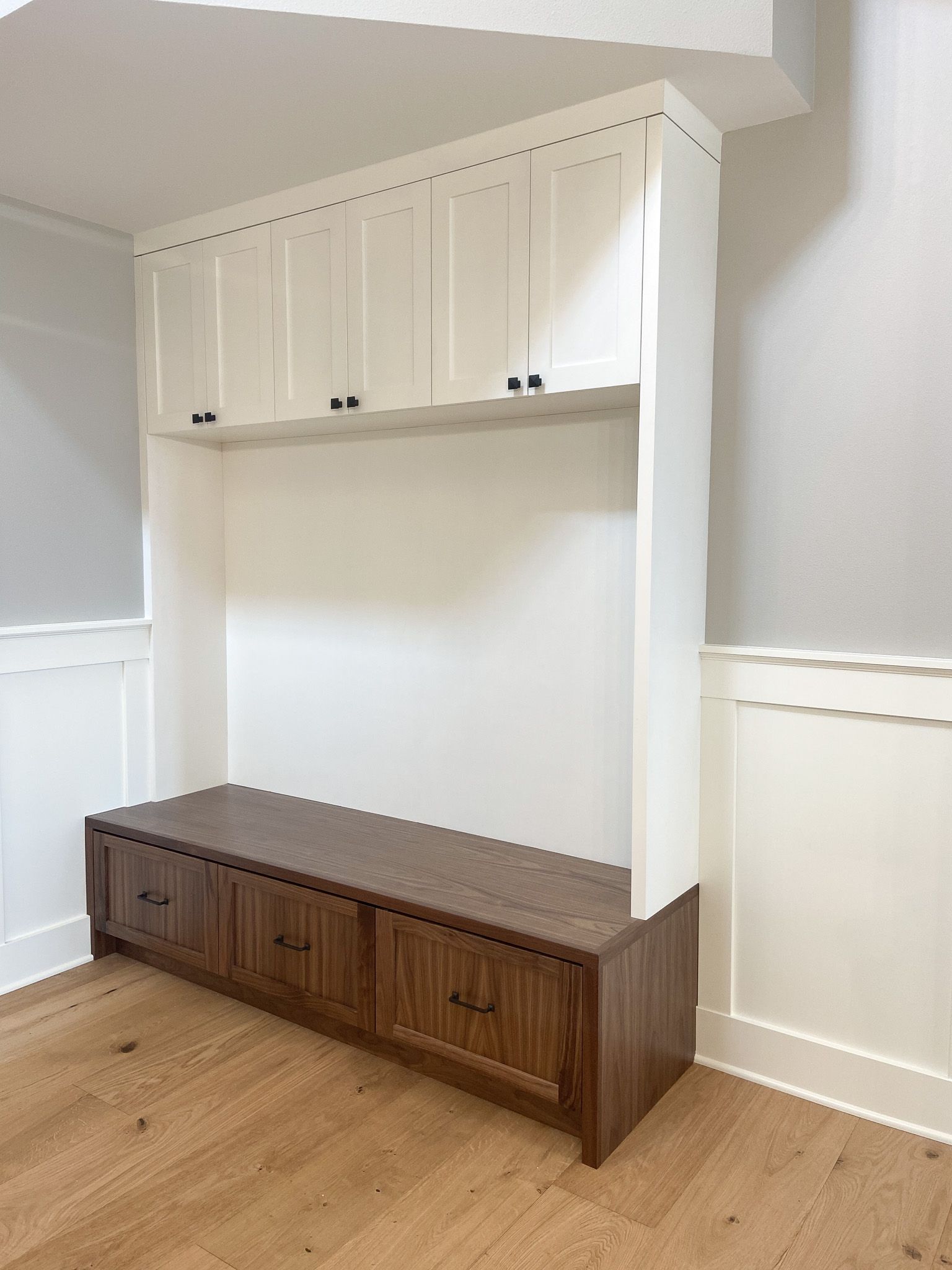 A room with a wooden bench and white cabinets.