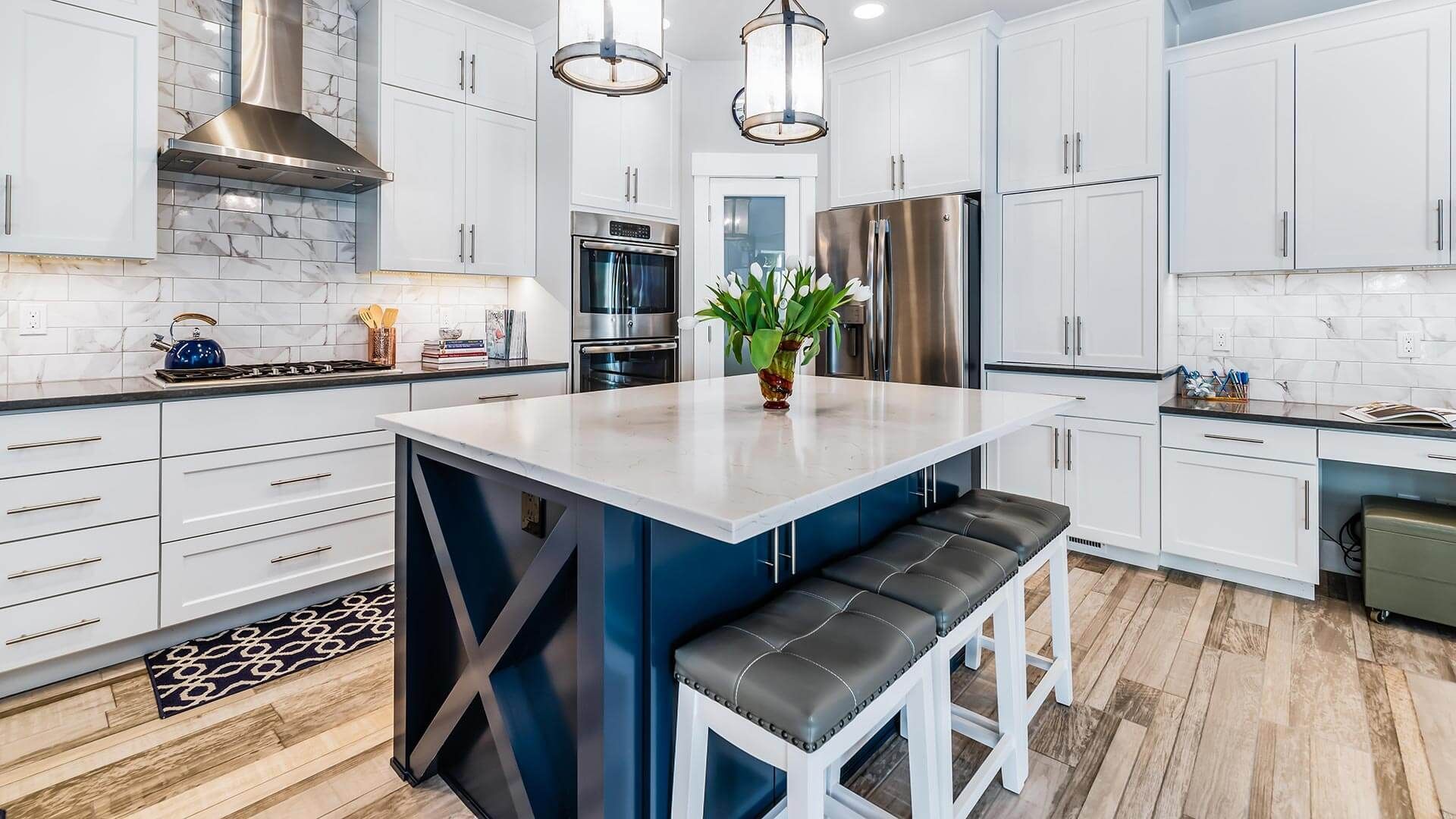 A kitchen with white cabinets and a blue island with benches.