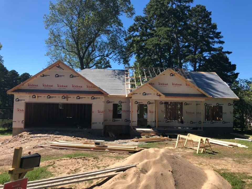 New house under construction with roof and walls covered in protective material.