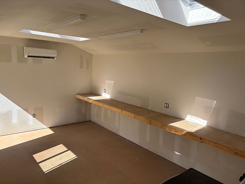 Empty, bright workshop with skylights, long wooden counter, and AC unit.