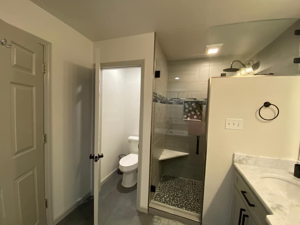 Bathroom interior with a shower, toilet, and vanity. Gray walls and flooring.