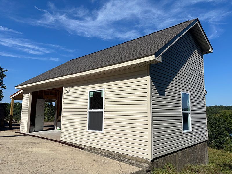 A partially built two-story building with tan and gray siding under a blue sky.