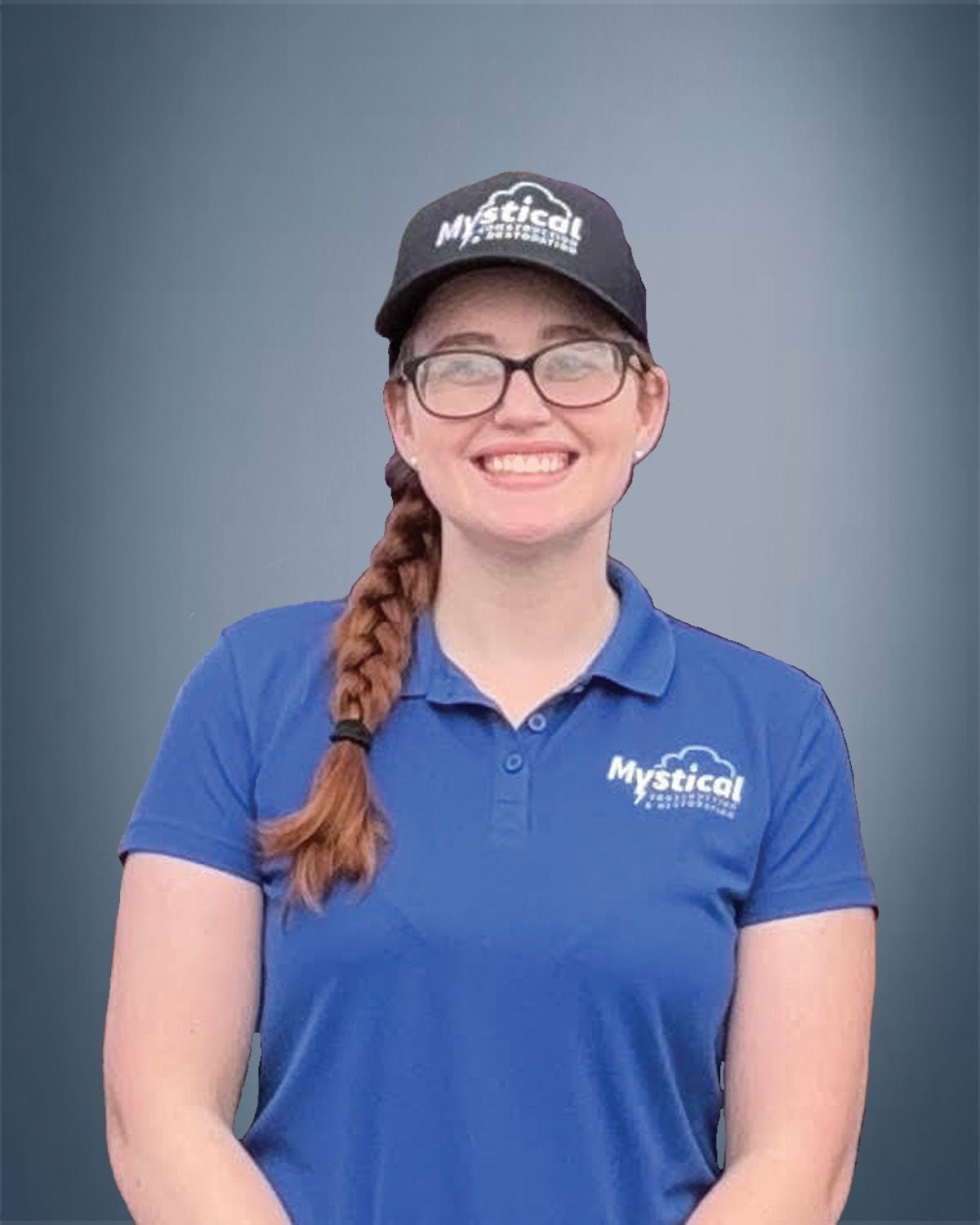 Woman wearing a blue polo shirt and cap with the logo "Mystical Properties." She smiles.