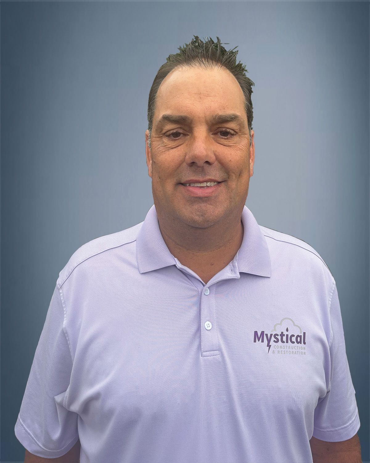 Man in a purple polo shirt smiling; logo for "Mystical" on shirt.