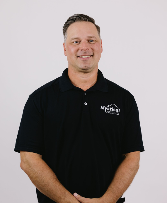 Smiling person in a black polo shirt standing against a light background
