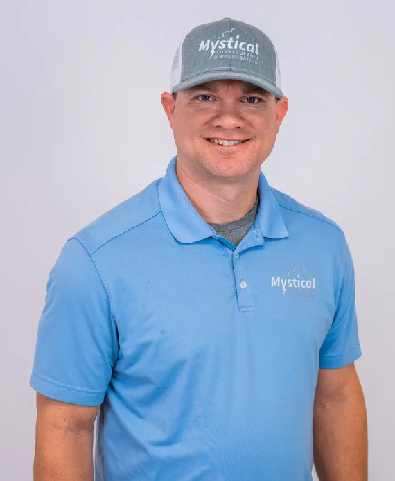 Smiling man in a blue polo and gray Mystical cap against a light background