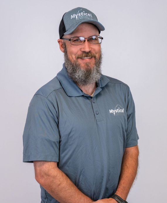 Smiling man in gray polo and cap against a light background