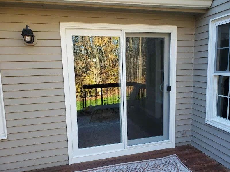 Sliding glass patio door on a house with beige siding and a small porch mat