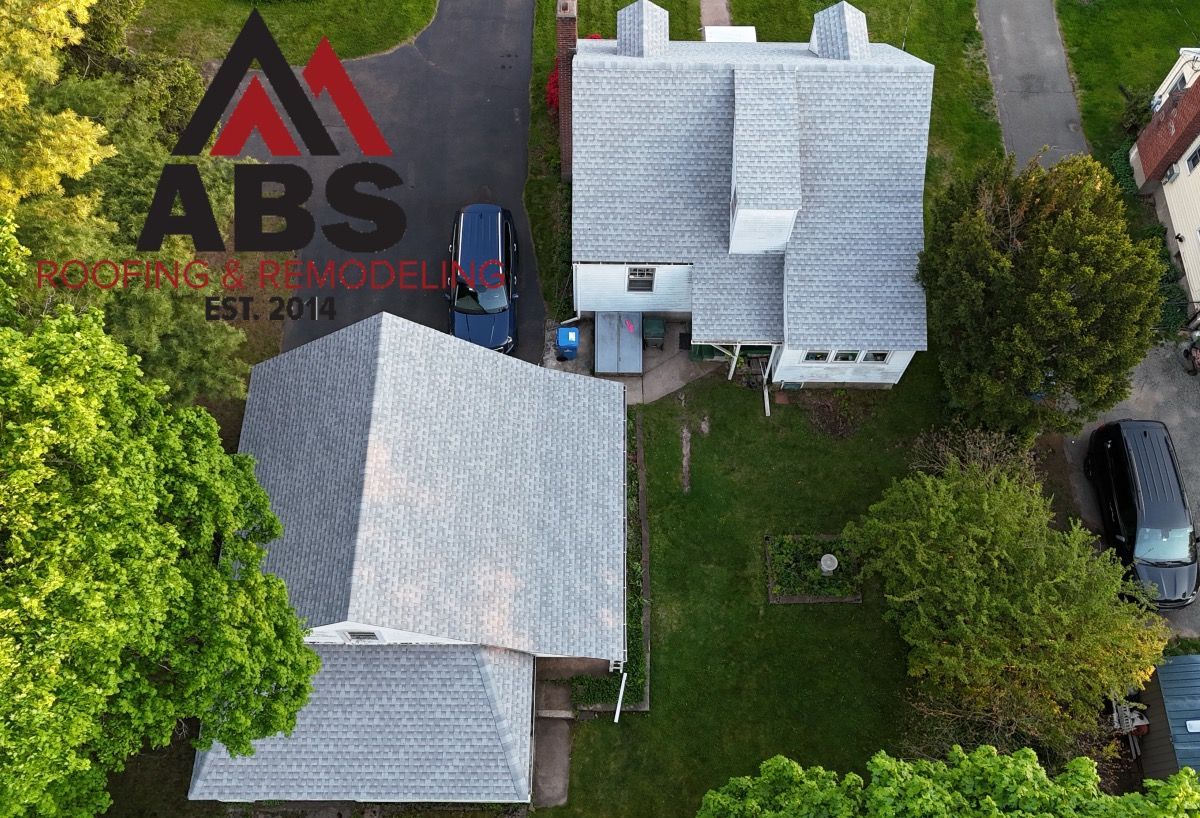 Aerial view of two light-roofed houses with green yard and parked cars