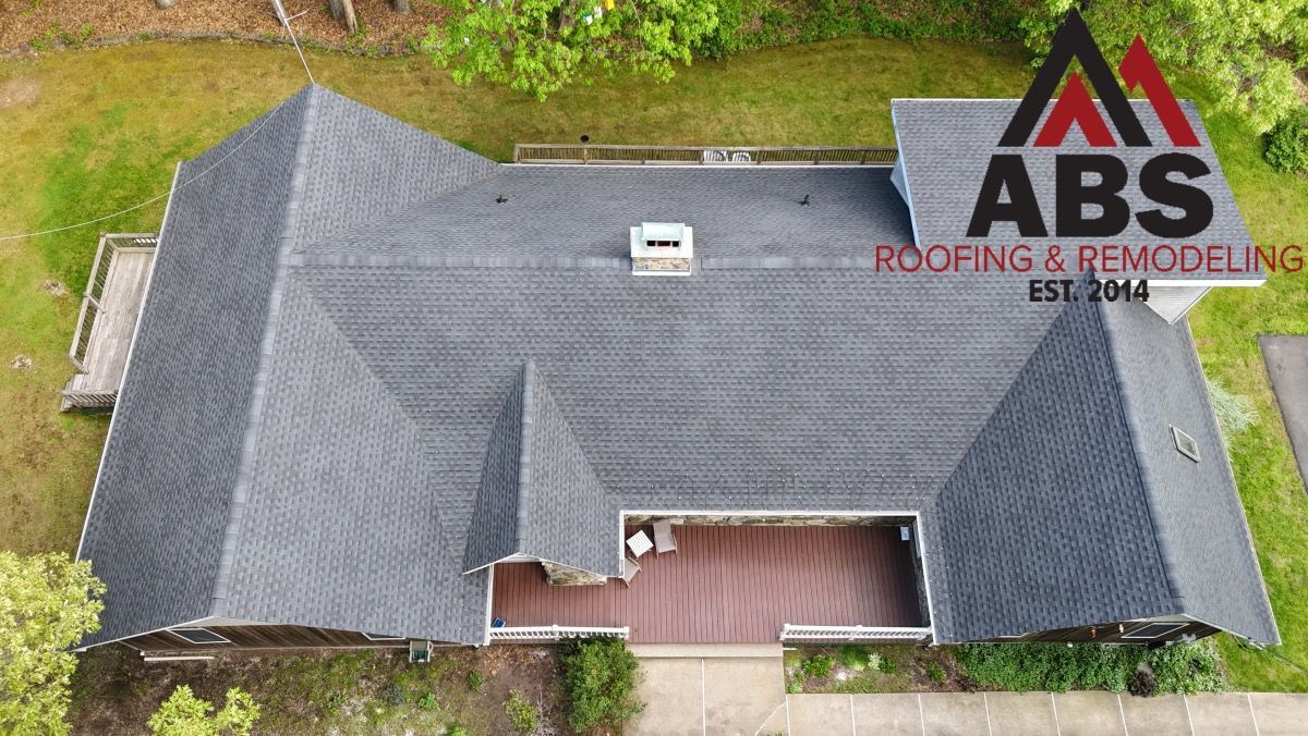 Aerial view of a gray shingle roof with a red porch and ABS Roofs & Remodeling logo watermark
