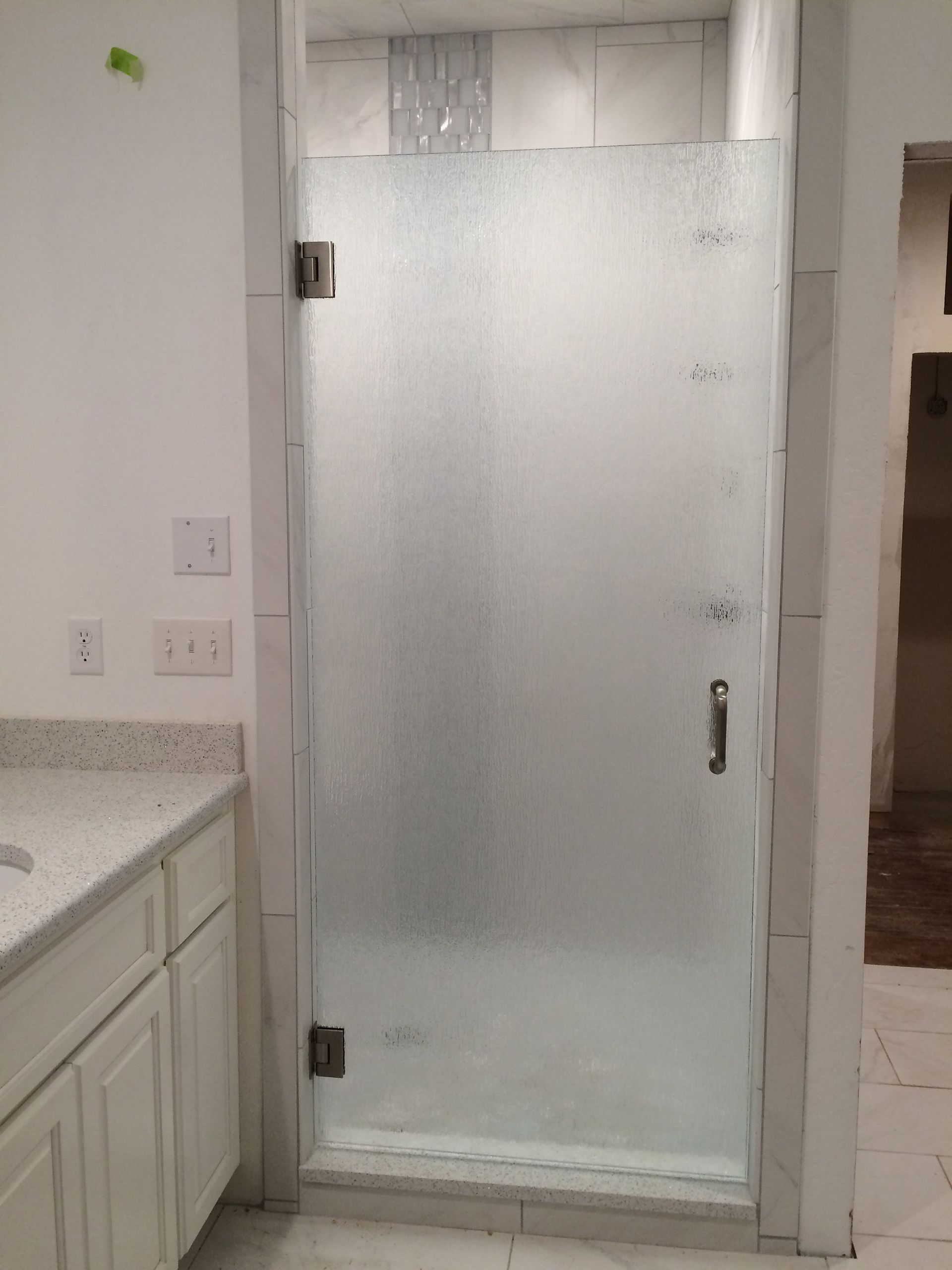 A bathroom with a glass shower door and a sink.
