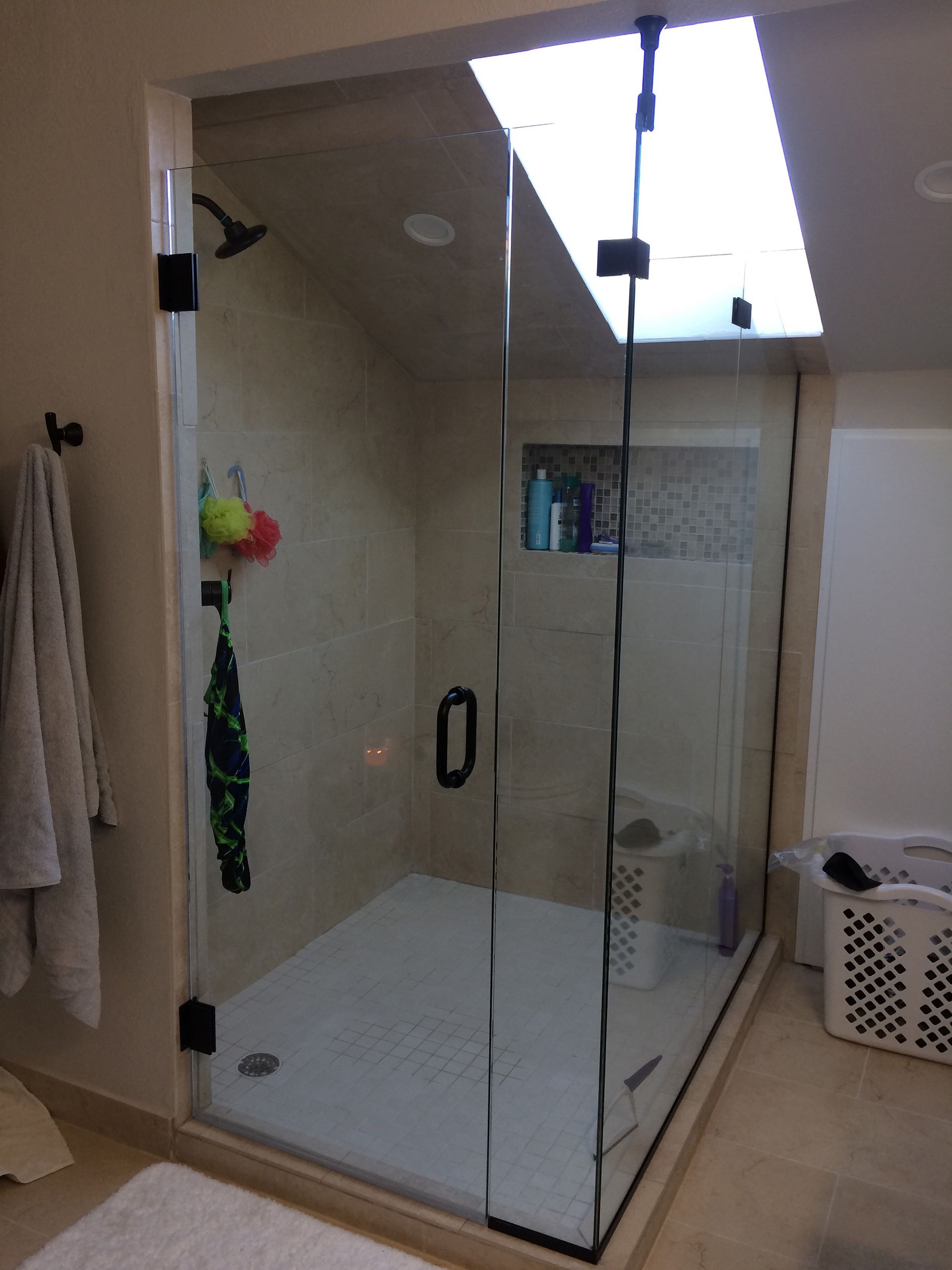 A bathroom with a walk in shower and a laundry basket