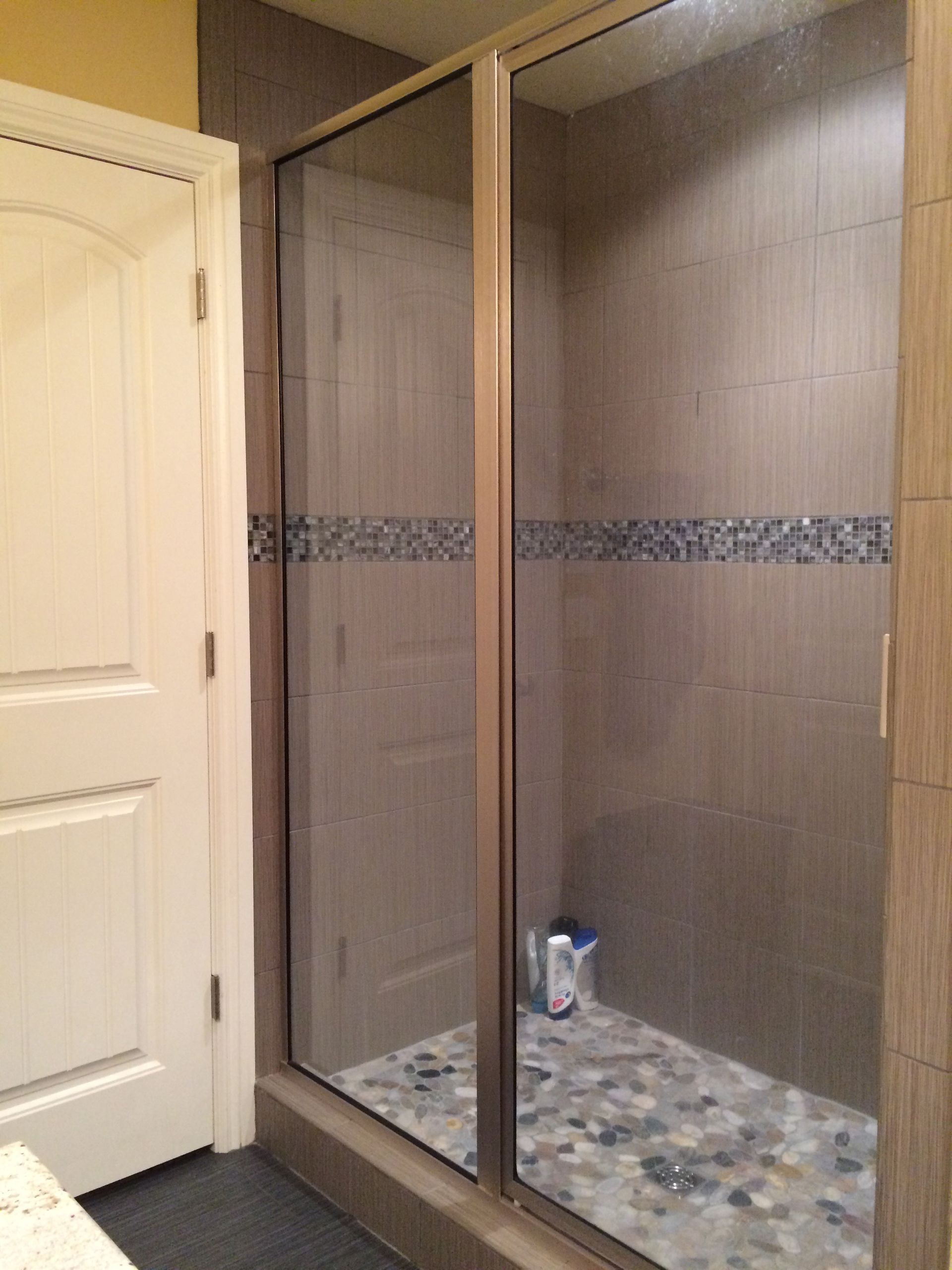 A bathroom with a walk in shower and a mirror.