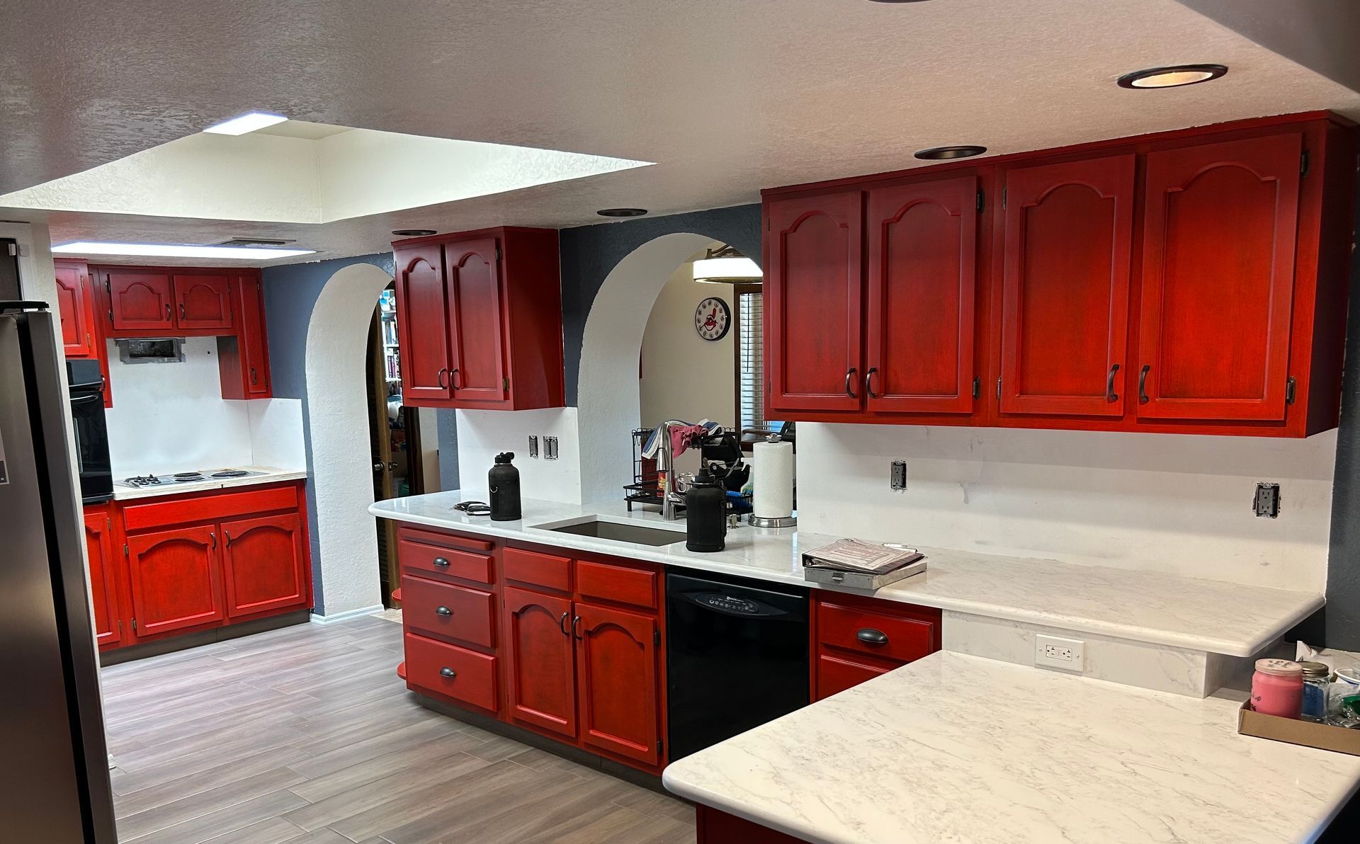 Kitchen with red cabinets, white countertops, and stainless steel appliances.