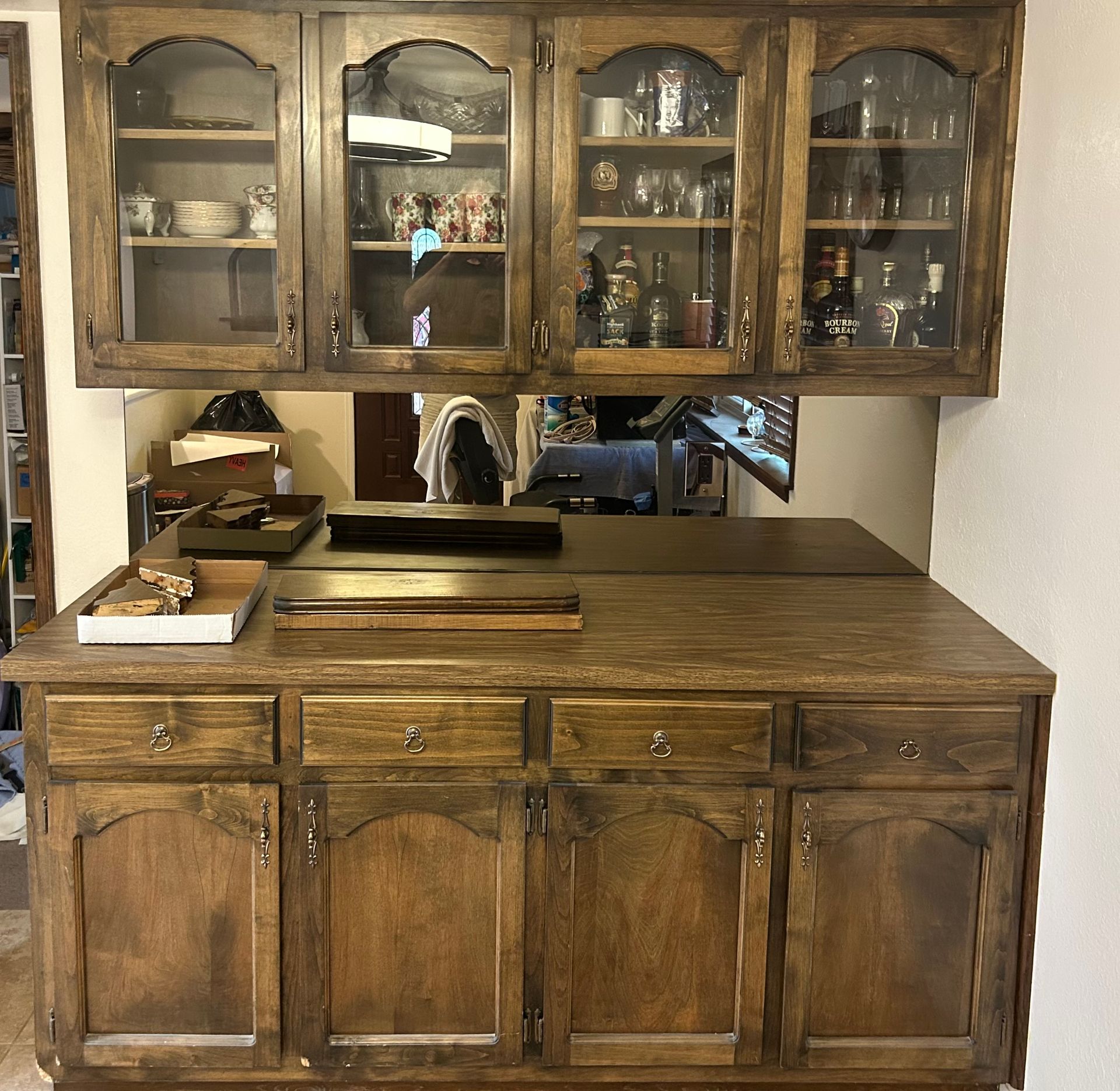 Vintage wooden kitchen cabinet with glass-front hutch, shelves, and countertops in a home interior.