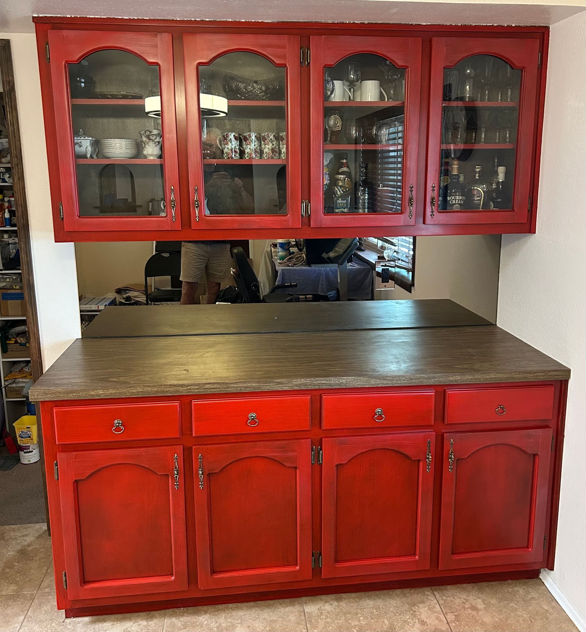 Red kitchen hutch with glass-front upper cabinets and wooden lower cabinets in a room setting