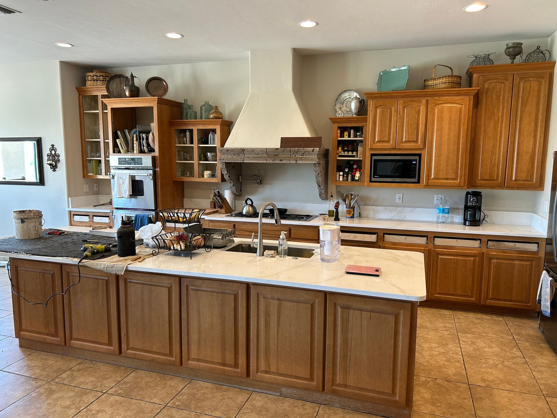 Large kitchen with wood cabinets, granite island, stainless fridge, and tiled floor.