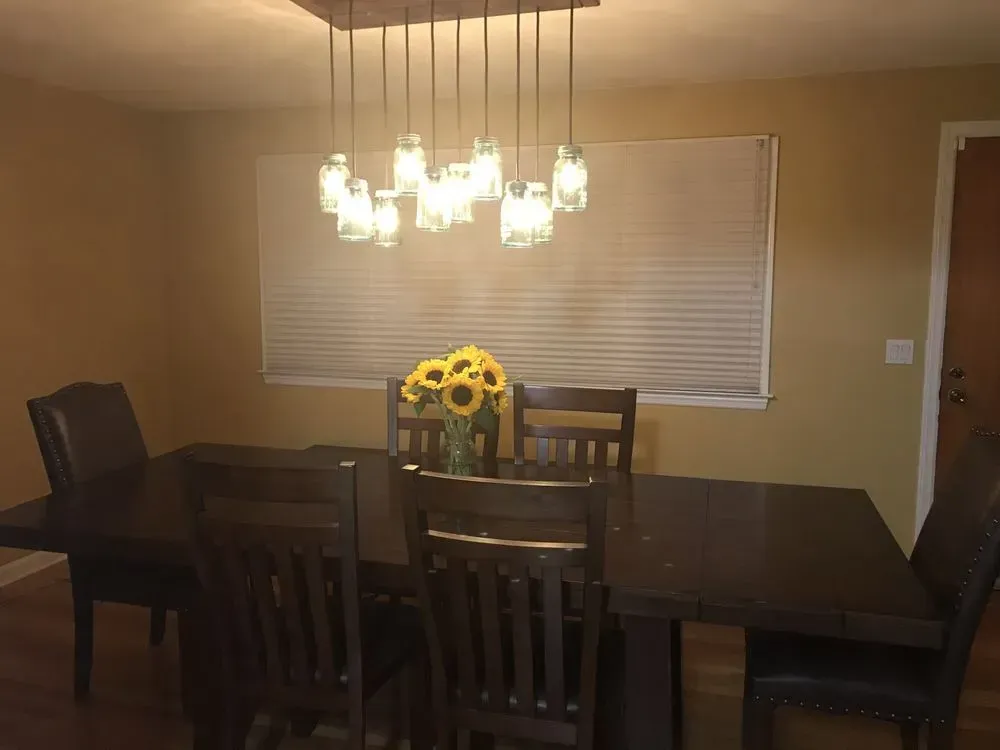 a dining room table and chairs with a vase of sunflowers on it