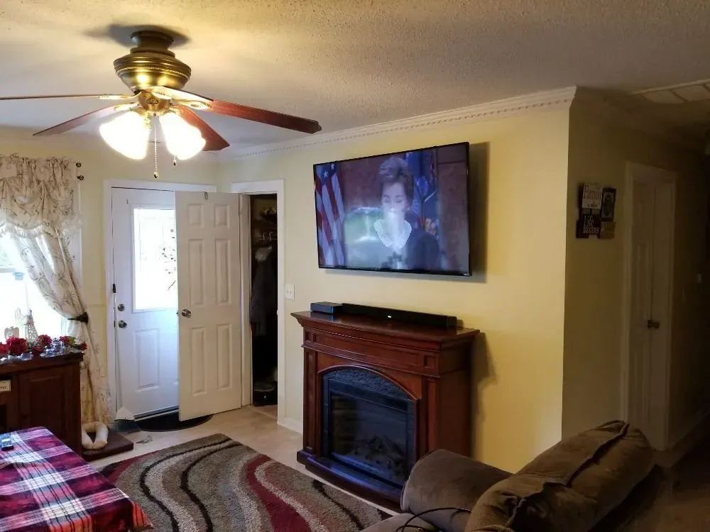 a living room with a fireplace, couch, television, and ceiling fan