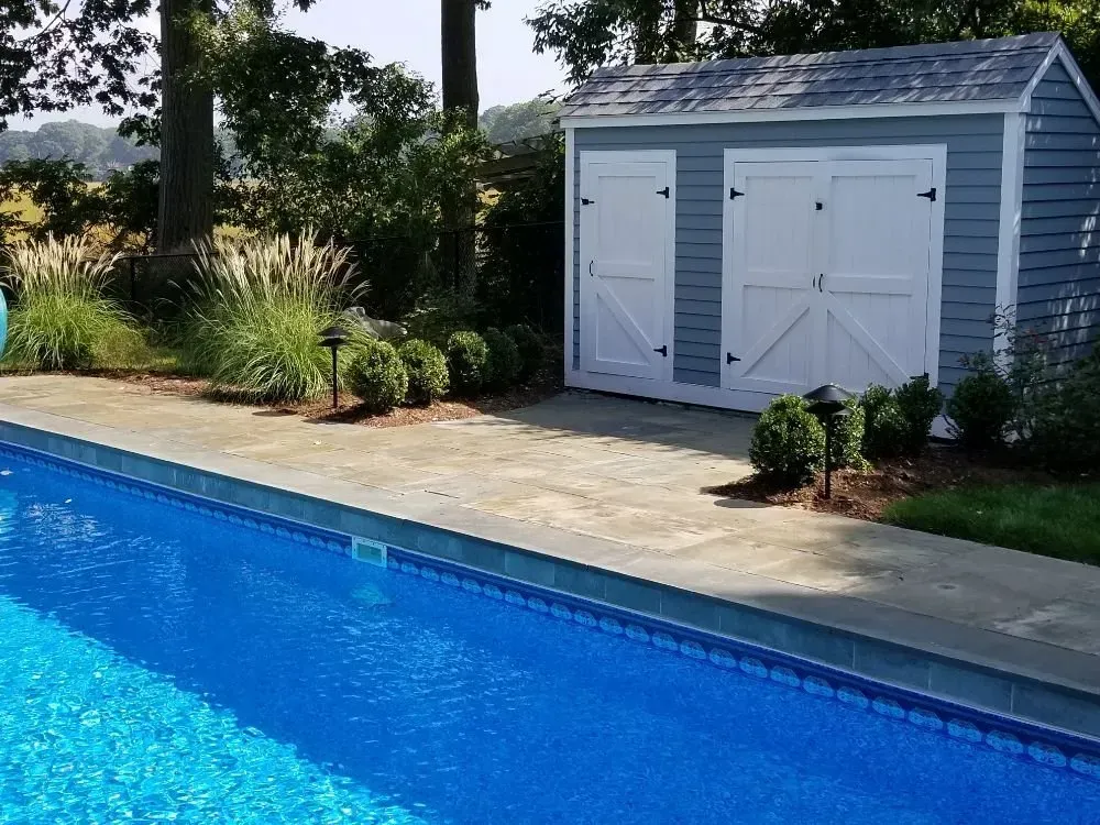 a shed sits next to a large swimming pool