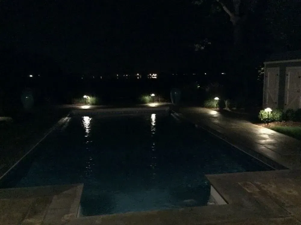 a large swimming pool is lit up at night