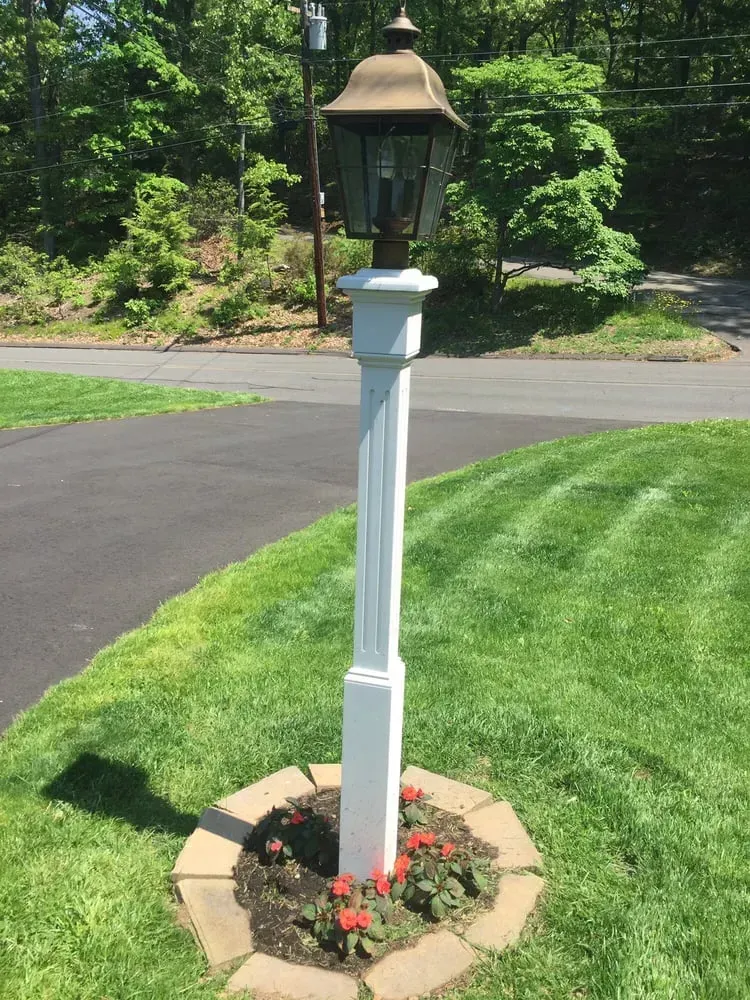 a white lamp post is sitting in the middle of a lush green lawn