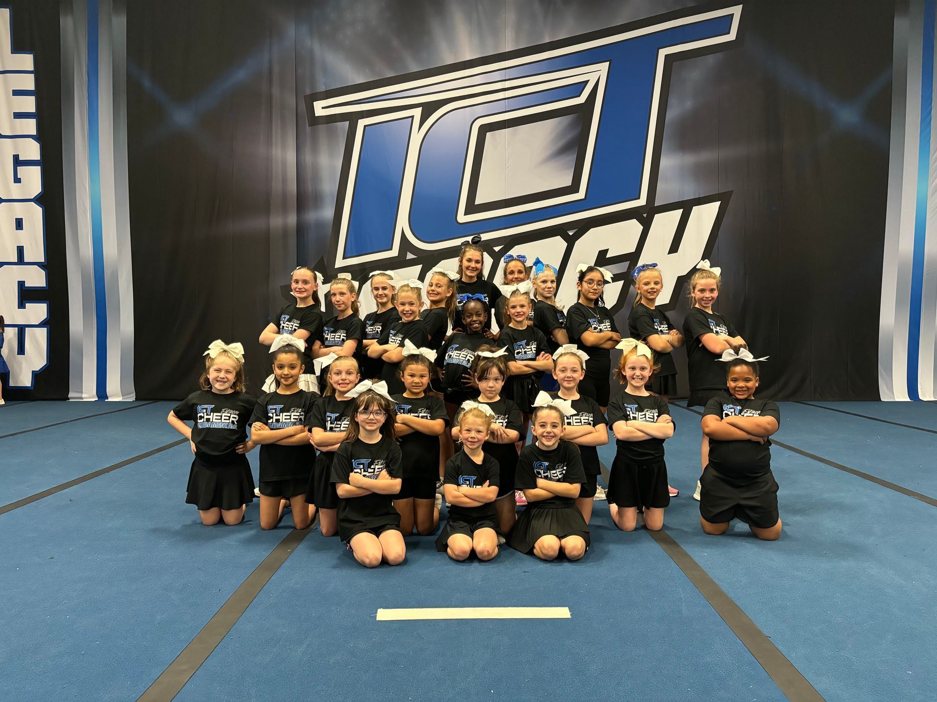 A group of cheerleaders are posing for a picture in front of a tct logo