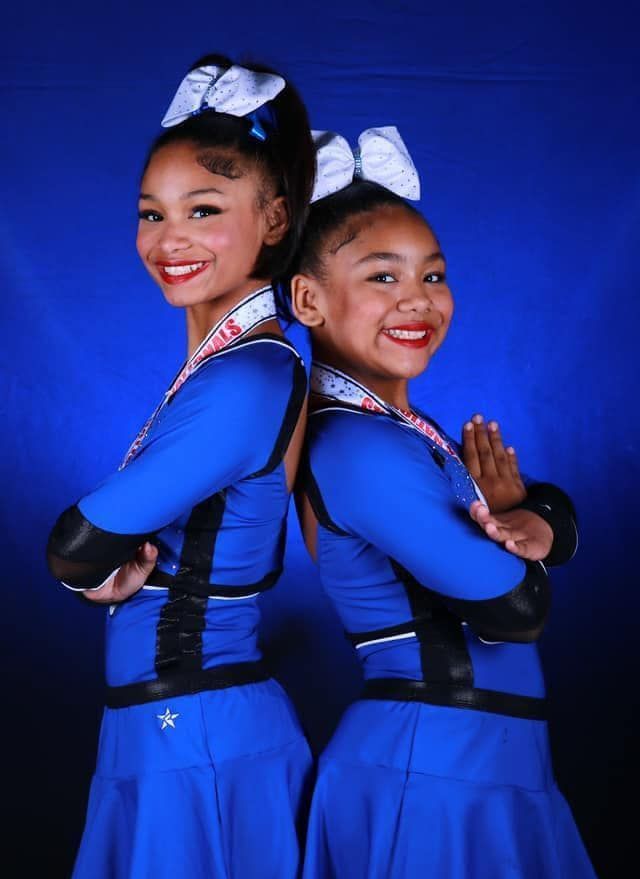 Two cheerleaders are posing for a picture with their arms crossed