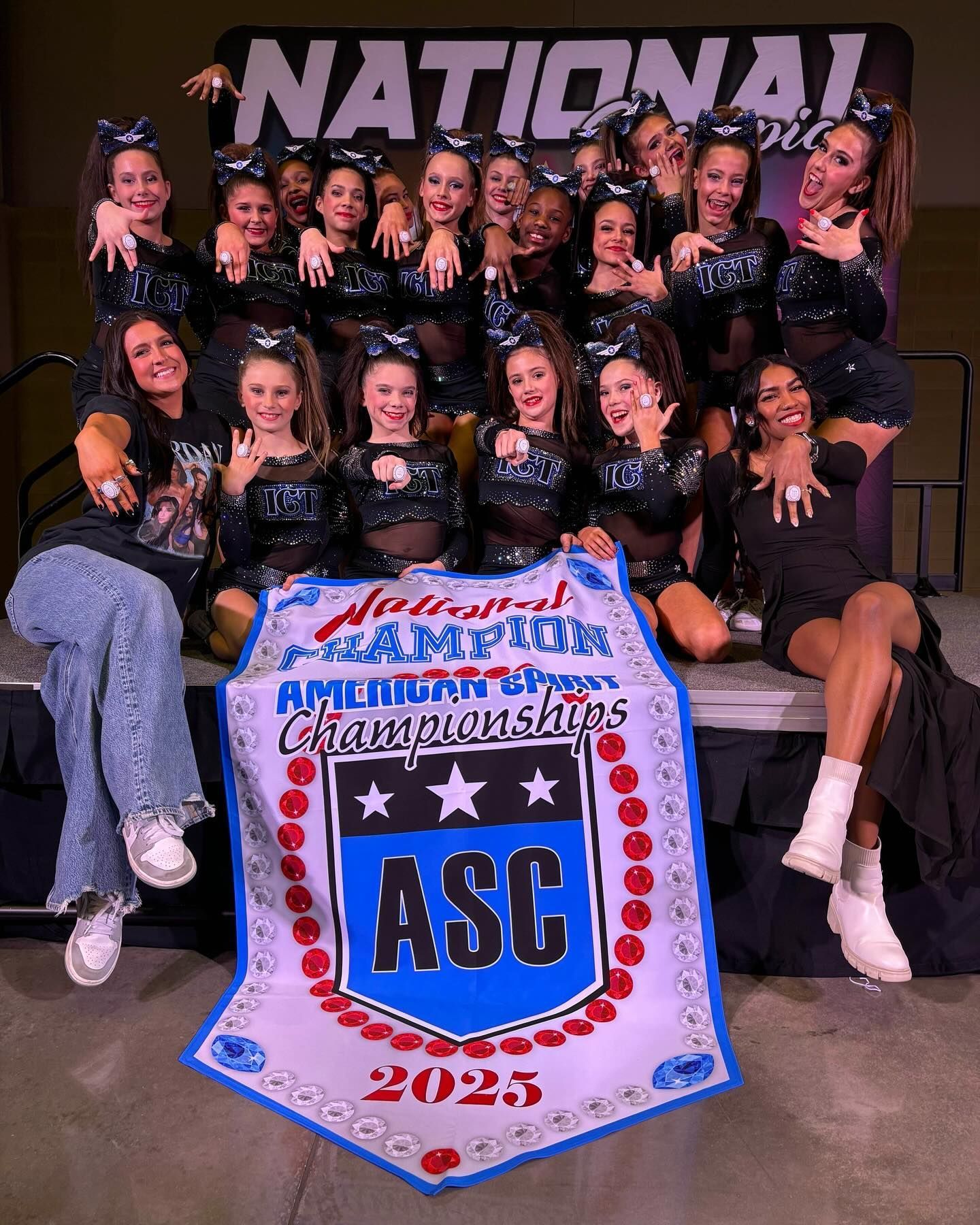 A group of cheerleaders are posing for a picture with a banner that says asc.